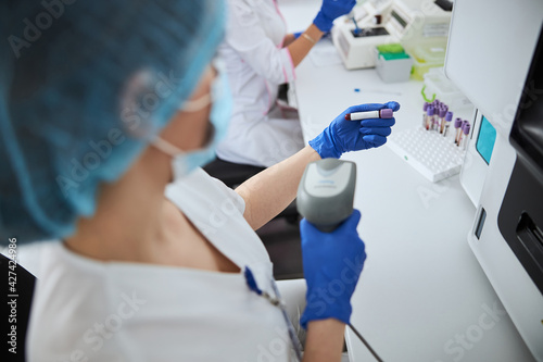Female biochemist scanning the blood sample vacutainer