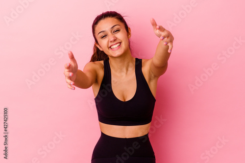 Young sport Indian woman isolated on pink background feels confident giving a hug to the camera.