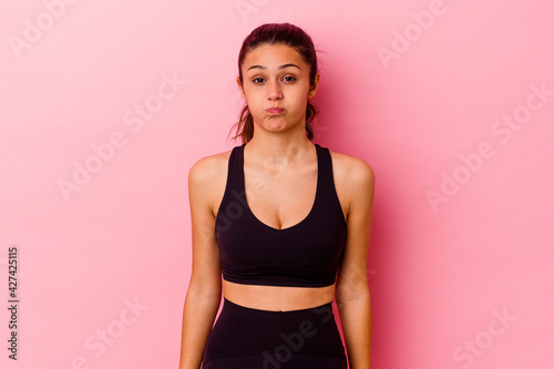 Young sport Indian woman isolated on pink background blows cheeks  has tired expression. Facial expression concept.