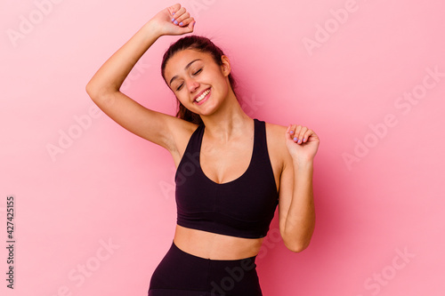 Young sport Indian woman isolated on pink background celebrating a special day, jumps and raise arms with energy.