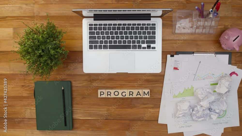 Word program is collected from wooden cubes in the workplace next to a laptop and work papers. Concept of planning and projecting. Word program is collected from wooden cubes in the workplace next to a laptop and work papers. Concept of planning and projecting.