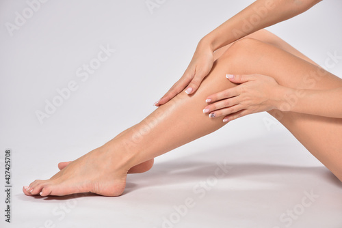 Woman touching her smooth legs after depilation, stock photo.