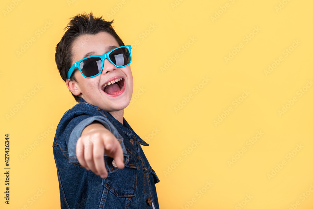 happy and smiling kid with sunglasses pointing with the finger and copy space happy and smiling kid with sunglasses pointing with the finger and copy space