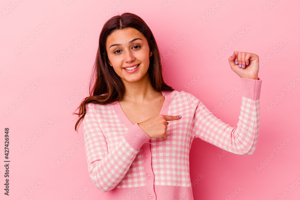 Young Indian woman isolated on pink background showing strength gesture with arms, symbol of feminine power Young Indian woman isolated on pink background showing strength gesture with arms, symbol of feminine power