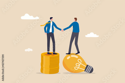 Idea pitching, fund raising and venture capital, selling business or merger agreement concept, entrepreneur businessman standing on lightbulb idea lamp shaking hands with VC on money coins stack. photo