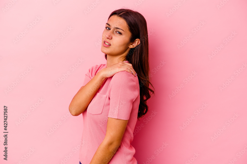 Young Indian woman isolated on pink background having a shoulder pain. Young Indian woman isolated on pink background having a shoulder pain.