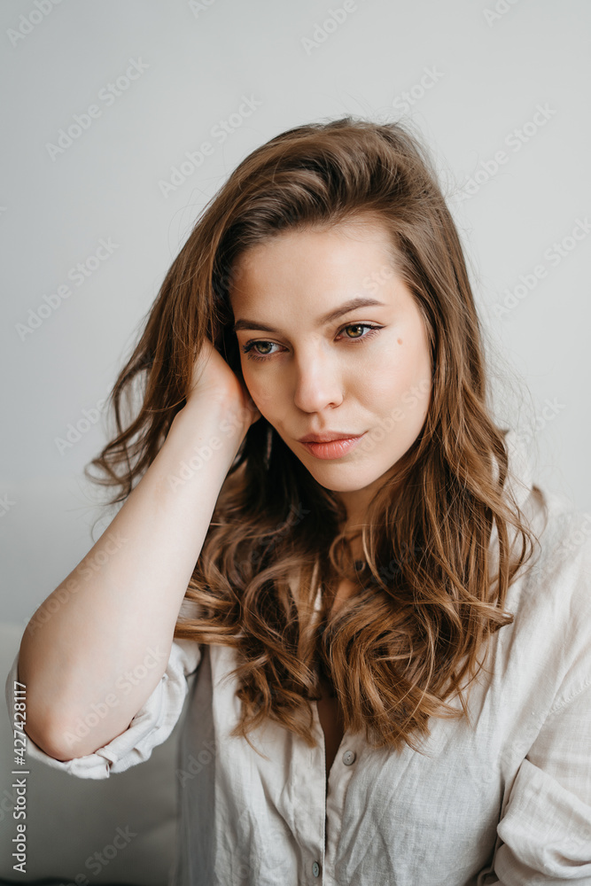Нoung woman is sitting on the sofa in the living room. A beautiful blonde in white comfortable home clothes. Нoung woman is sitting on the sofa in the living room. A beautiful blonde in white comfortable home clothes.