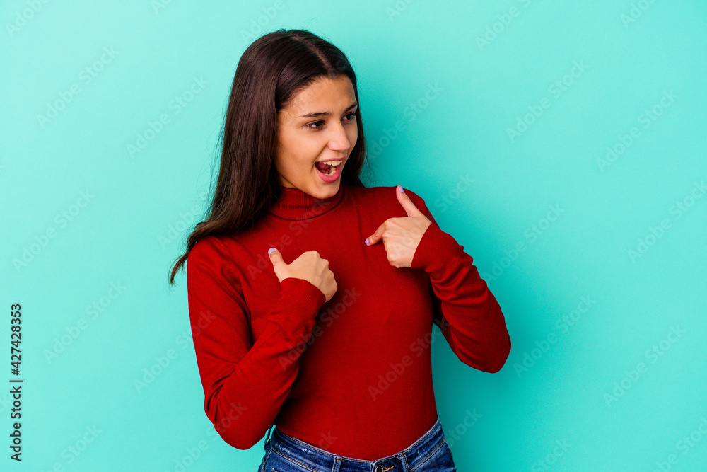 Young Indian woman isolated on blue background surprised pointing with finger, smiling broadly. Young Indian woman isolated on blue background surprised pointing with finger, smiling broadly.