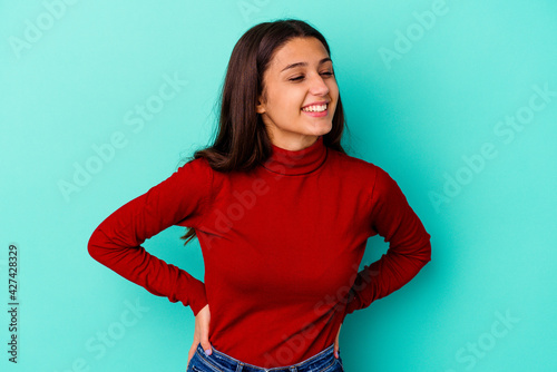 Young Indian woman isolated on blue background confident keeping hands on hips.