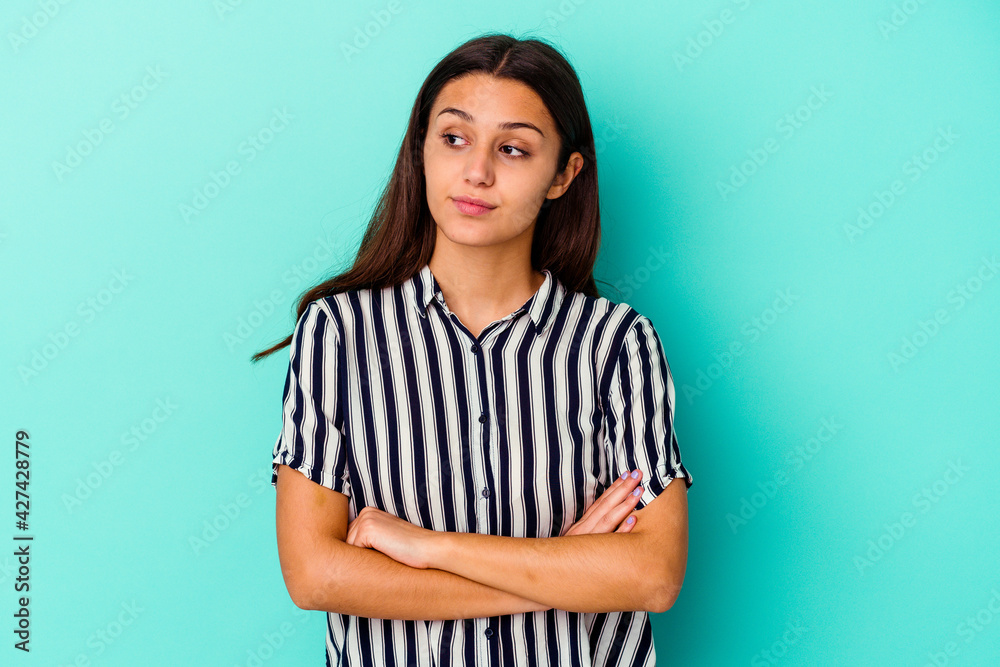 Young Indian woman isolated on blue background dreaming of achieving goals and purposes