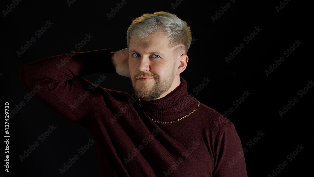 Handsome man in stylish blouse looking at camera through hands, posing, feeling happiness, fun, enjoyment on black background. Facial expression of trendy bearded guy with gray hair. Modern fashion