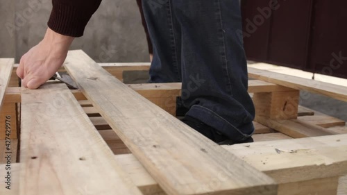 Wallpaper Mural A young man disassembles a pallet. A wooden pallet, garden furniture. A man rips off the boards to make a table. Cheap DIY master eco-friendly wasteless with their own hands can't hard tear off Torontodigital.ca
