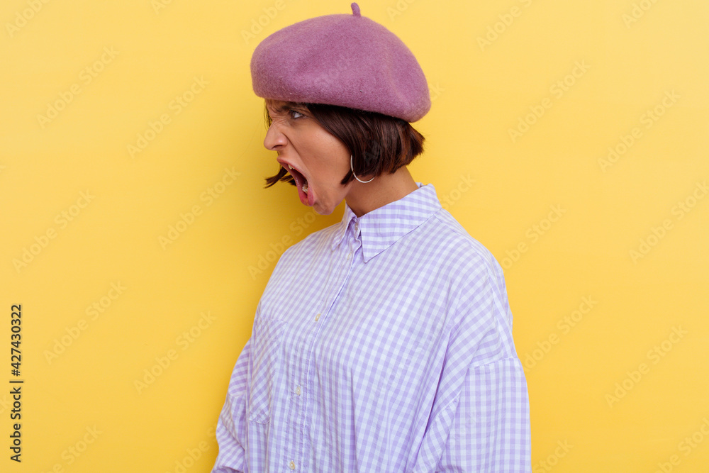Young mixed race woman wearing a beret isolated on yellow background shouting towards a copy space Young mixed race woman wearing a beret isolated on yellow background shouting towards a copy space
