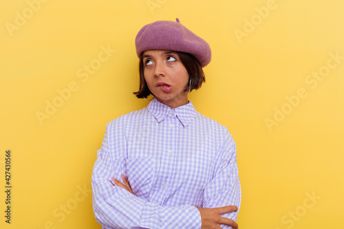 Young mixed race woman wearing a beret isolated on yellow background tired of a repetitive task.