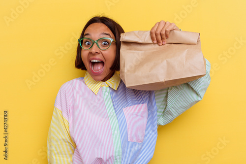 Photos Young student mixed race woman taking lunch isolated on yellow background