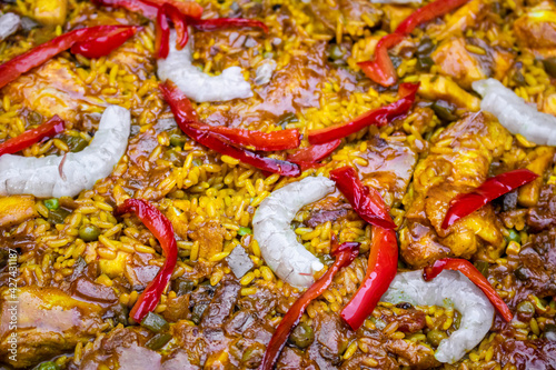Close up of Homemade Spanish typical Paella with prawns, peas, chicken and red pepper in a base of rice and vegetables. Traditional Spanish food. Yellow rice texture. Mediterranean food.