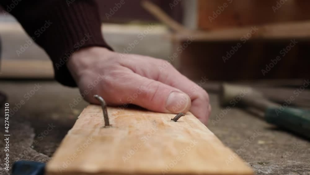 A young man pulls nails out of a wooden board. Pallet. Tick tool concrete A young man pulls nails out of a wooden board. Pallet. Tick tool concrete