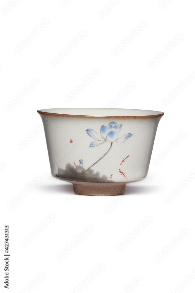 Subject shot of white ceramic bowl with crazing and decorated with picture of blue lotus flower painted in Chinese style. Graceful tea bowl is isolated on the white background. Subject shot of white ceramic bowl with crazing and decorated with picture of blue lotus flower painted in Chinese style. Graceful tea bowl is isolated on the white background.