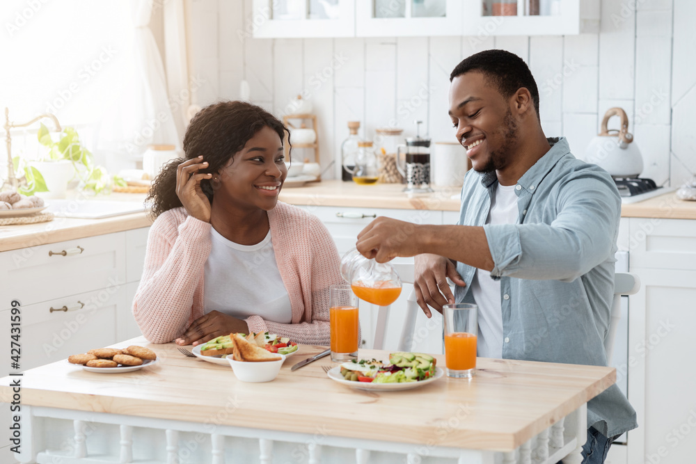Happy Young Millennial Spouses Chatting While Having Breakfast At Home Together