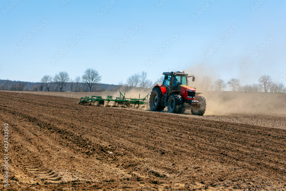 Modern tractor pulling a large plow . Springtime agricultural working Modern tractor pulling a large plow . Springtime agricultural working