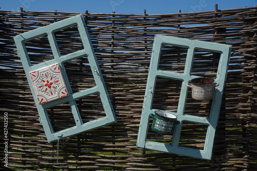 old wooden windows painted on a twig fence. exterior decoration in the courtyard of a boarding house in Vama Veche, Romania.