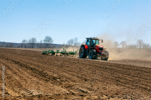 Modern tractor pulling a large plow . Springtime agricultural working 