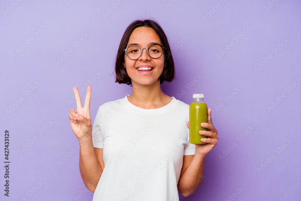 Young mixed race woman holding a healthy smoothie isolated on purple background showing number two with fingers. Young mixed race woman holding a healthy smoothie isolated on purple background showing number two with fingers.