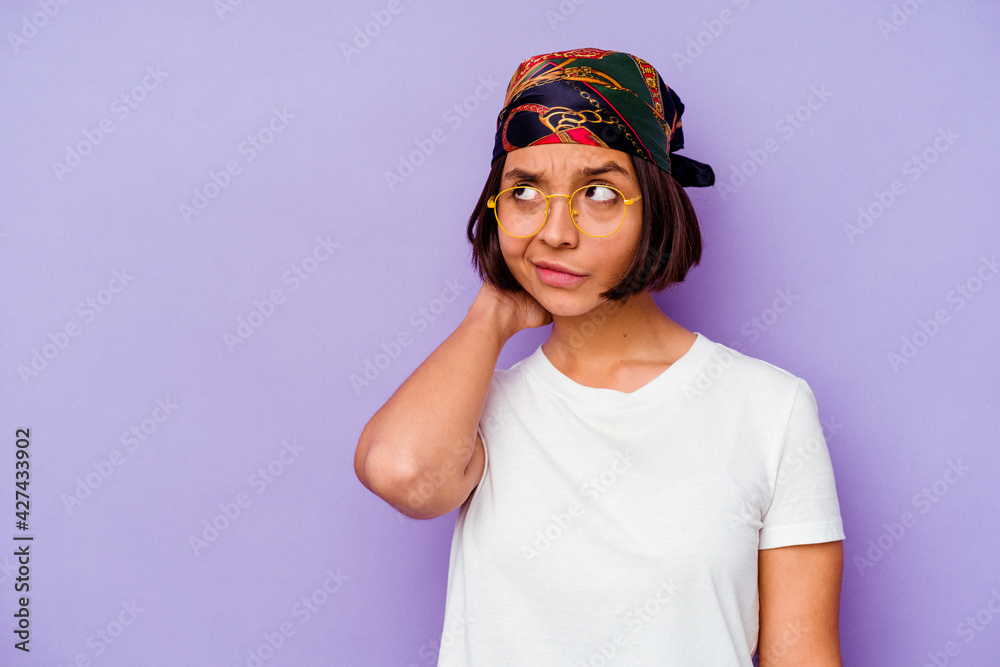 Young mixed race woman wearing a bandana isolated on purple background touching back of head, thinking and making a choice. Young mixed race woman wearing a bandana isolated on purple background touching back of head, thinking and making a choice.