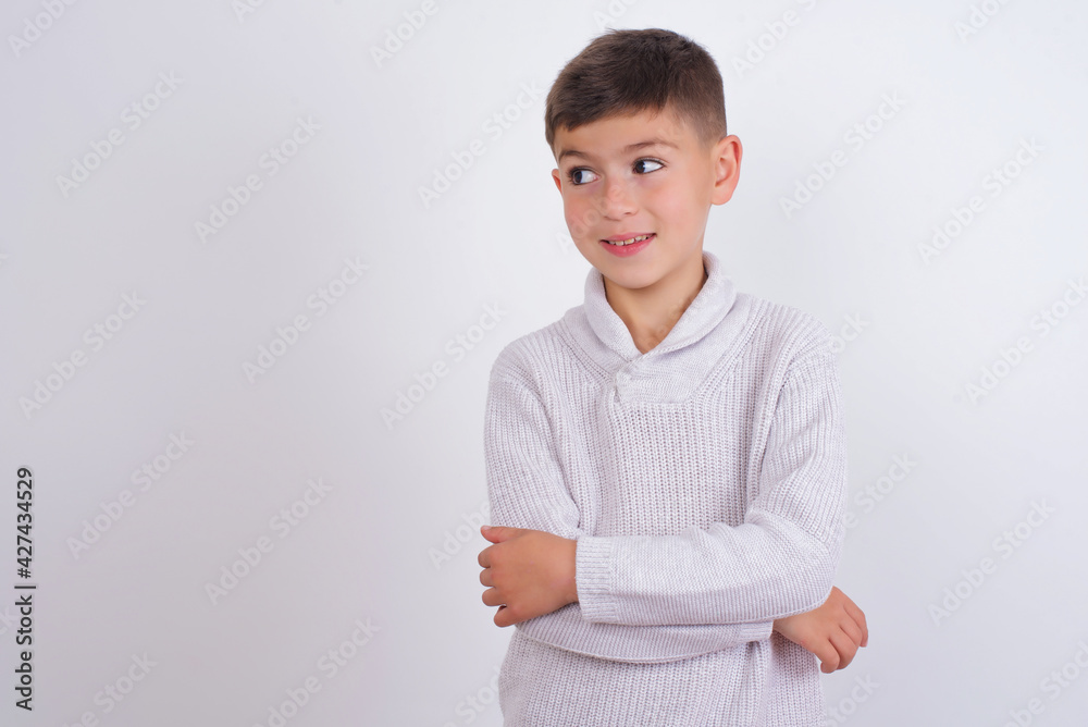 Dreamy rest relaxed Caucasian kid boy wearing knitted sweater against white wall crossing arms, looks good copyspace Dreamy rest relaxed Caucasian kid boy wearing knitted sweater against white wall crossing arms, looks good copyspace