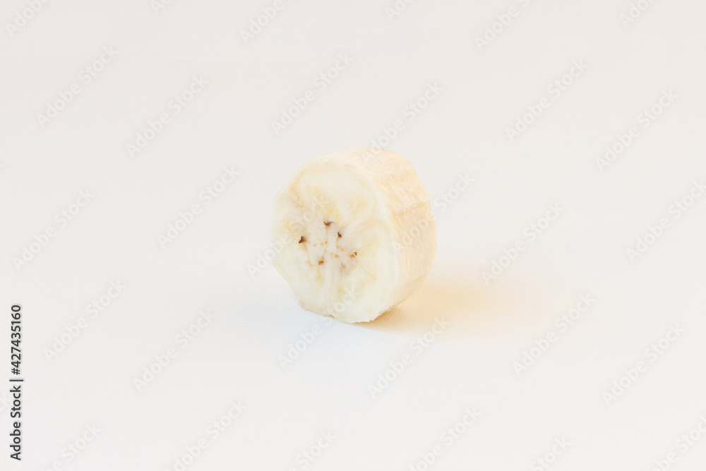 A slice of unpeeled banana isolated on white background. Skewed view. A slice of unpeeled banana isolated on white background. Skewed view.