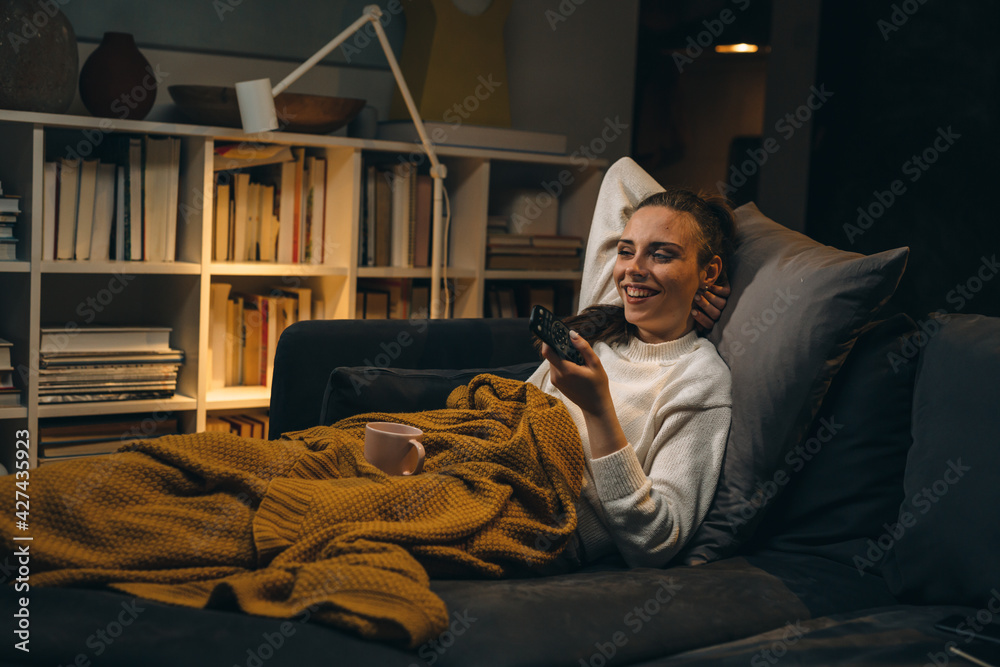 woman watching television relaxed on sofa at her home woman watching television relaxed on sofa at her home