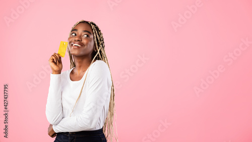 Black woman holding credit card and dreaming photo