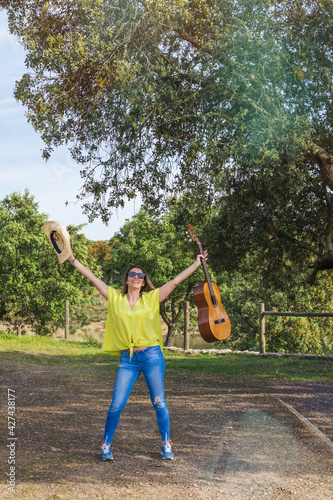 Beautiful Young Woman Enjoying A Nice Day In A Natural Park. She Has A Cowboy Hat And A Spanish Guitar. People And Nature