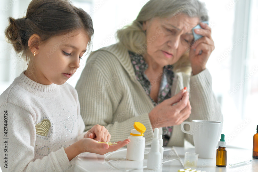 Cute girl giving medicine to sick senior woman Cute girl giving medicine to sick senior woman