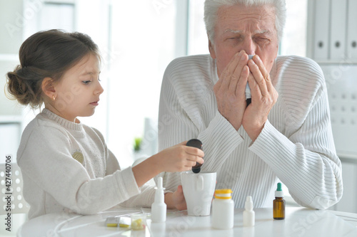 Granddaughter giving medicine to her grandfather in room