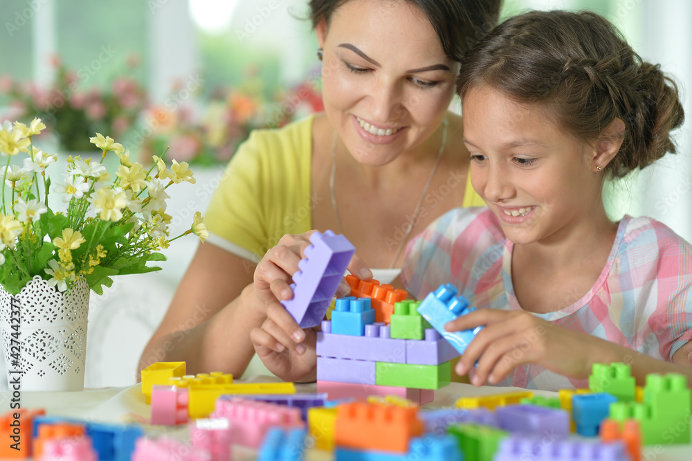 little daughter and mother playing with colorful plastic blocks at home little daughter and mother playing with colorful plastic blocks at home