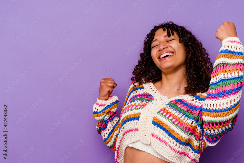 Young mixed race woman isolated on purple background raising fist after a victory, winner concept. Young mixed race woman isolated on purple background raising fist after a victory, winner concept.