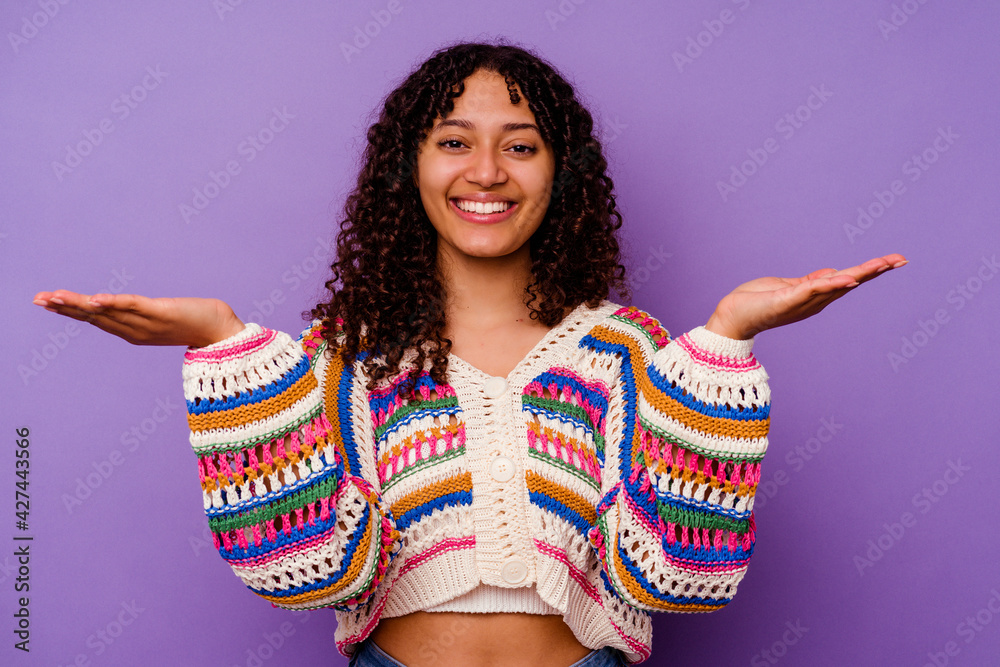 Young mixed race woman isolated on purple background makes scale with arms, feels happy and confident. Young mixed race woman isolated on purple background makes scale with arms, feels happy and confident.