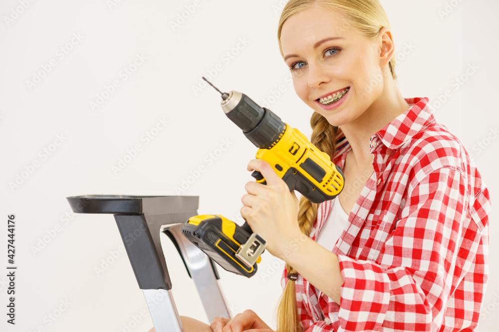 Woman on ladder using drill Woman on ladder using drill