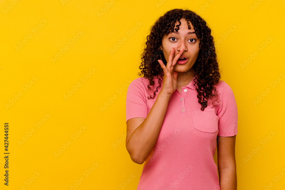 Young mixed race woman isolated on yellow background is saying a secret hot braking news and looking aside Young mixed race woman isolated on yellow background is saying a secret hot braking news and looking aside
