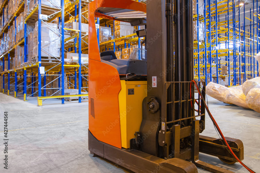 Electrical forklift loader charging in the warehouse. Pallet stacker truck equipment inside of a modern warehouse storage Electrical forklift loader charging in the warehouse. Pallet stacker truck equipment inside of a modern warehouse storage