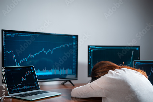 tired female beginner trader sleeping near monitor with stock chart at workplace