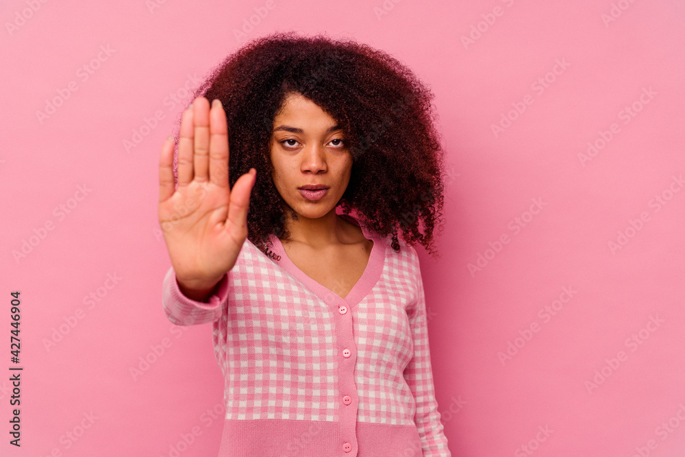 Young african american woman isolated on pink background standing with outstretched hand showing stop sign, preventing you.