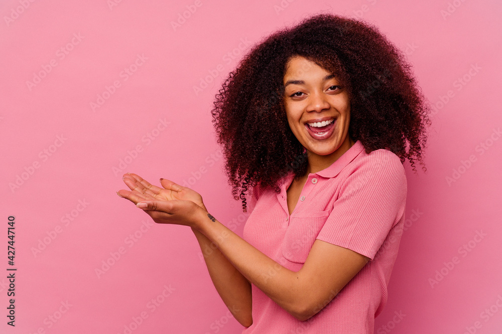 Young african american woman isolated on pink background holding a copy space on a palm. - obrazy, fototapety, plakaty 