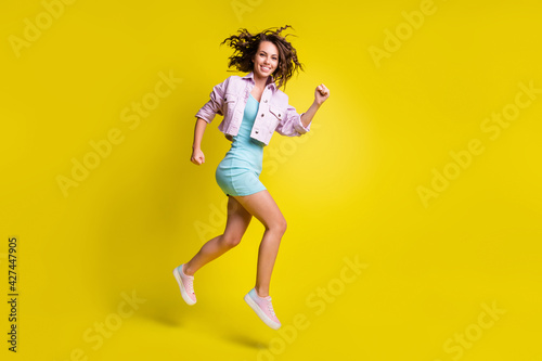 Full length profile portrait charming cheerful girl running look camera isolated on yellow color background