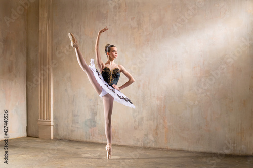Fototapeta Naklejka Na Ścianę i Meble -  Young ballerina in white tutu dancing in a spotlight in vintage scene