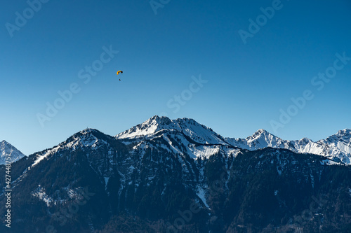 Paragleiter über dem Walgau, Para glider over the valley of Ill, with the mountains from Brand in the background. Zimba und Mondspitze, verschneite Berge im Hintergrund