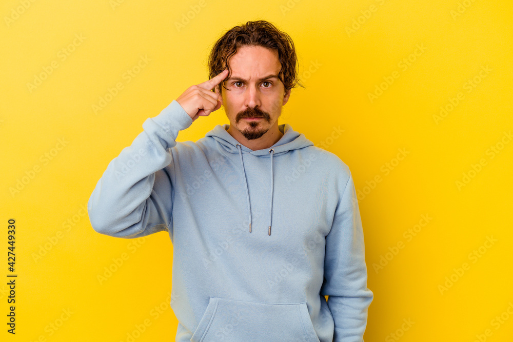Young caucasian man isolated on yellow background pointing temple with finger, thinking, focused on a task. Young caucasian man isolated on yellow background pointing temple with finger, thinking, focused on a task.