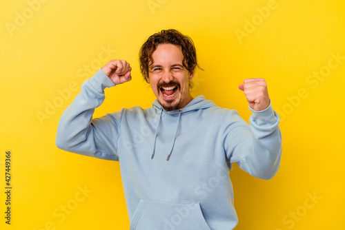 Young caucasian man isolated on yellow background dancing and having fun.