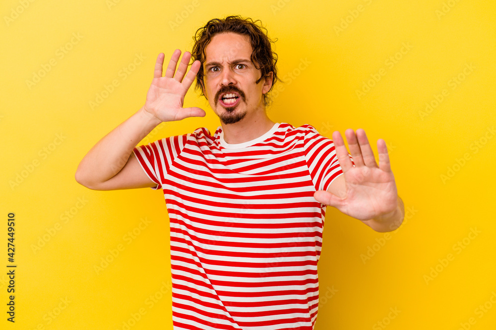 Young caucasian man isolated on yellow background being shocked due to an imminent danger Young caucasian man isolated on yellow background being shocked due to an imminent danger